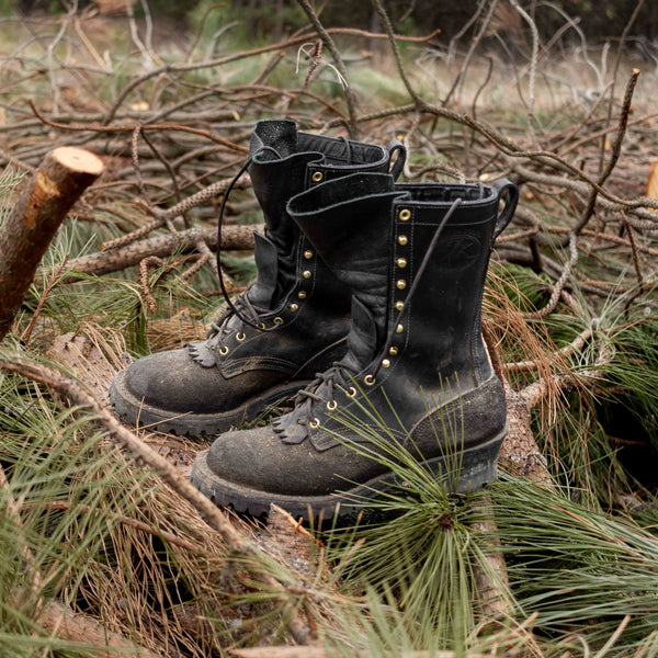 Pair of Fire Inlander black work boots on top of pine tree branches